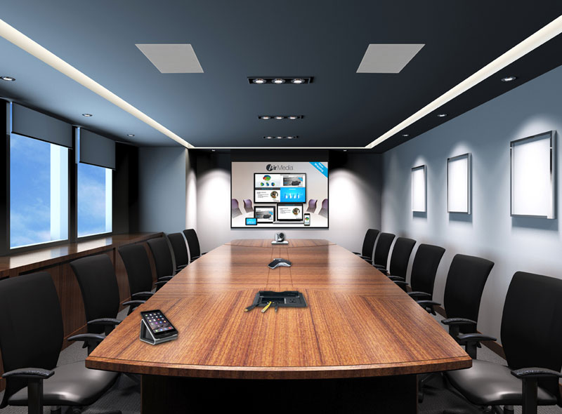 salas-reunioes-01 Elegant conference room with a long wooden table, beige chairs, a ceiling-mounted projector, and a large wall screen displaying a cityscape.